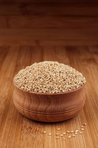 Quinua en cuenco de madera sobre tabla de bambú marrón, de cerca. Estilo rústico, sano fondo grañones dietéticos . — Foto de Stock