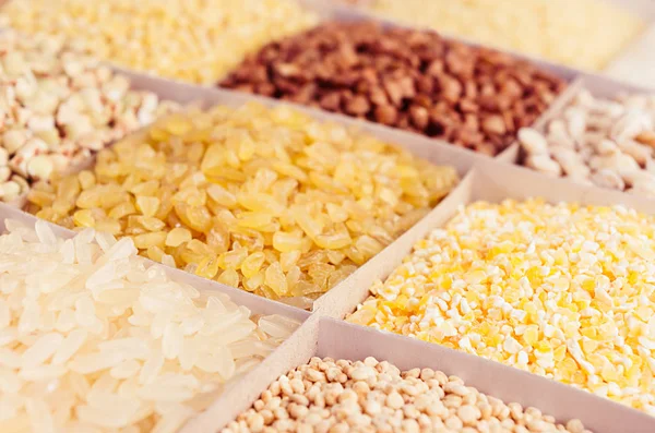 Surtido de diferentes groats como fondo, primer plano. Perla de trigo, bulgur, mijo, arroz, cuscús, sémola, sémola de maíz, trigo sarraceno, quinua . — Foto de Stock