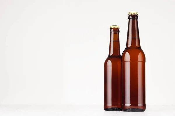 Två bruna longneck öl flaskor 500 ml och 330ml mock upp. Mall för reklam, design, branding identitet på vitt trä bord. — Stockfoto