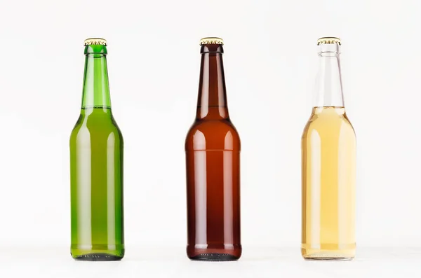 Collezione bottiglie di birra collo lungo 500ml diversi colori, mock up. Modello per pubblicità, design, identità di branding su tavolo in legno bianco . — Foto Stock