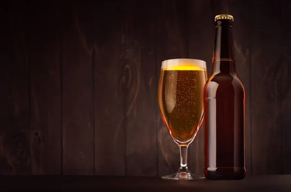 Пляшка коричневого пива та скляний тюльпан із золотим лайном на дошці з темного дерева, копіювання простору, сміх . — стокове фото