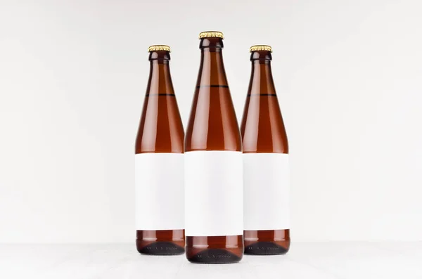 Три коричневі пляшки пива NRW 500 мл з порожньою білою етикеткою на білій дерев'яній дошці, сміються. Шаблон для реклами, дизайну, фірмового стилю . — стокове фото