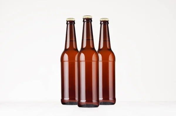 Grupp brun longneck ölflaskor 500ml mock upp. Mall för reklam, design, branding identitet på vitt trä bord. — Stockfoto
