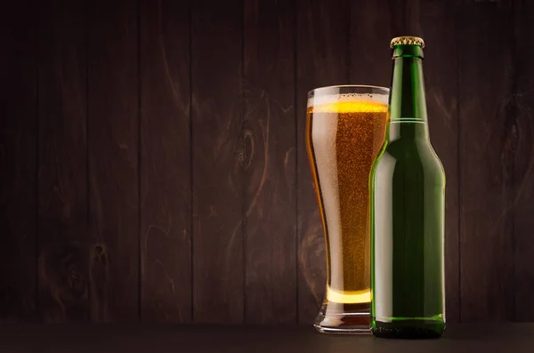 Пляшка зеленого пива та склянка з золотим лайном на темно-коричневій дерев'яній дошці, копіюють простір, глузують. Шаблон для реклами, дизайну, фірмового стилю . — стокове фото
