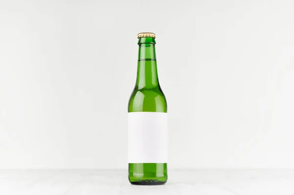 Frasco de cerveja verde longneck 330ml com etiqueta branca em branco na placa de madeira branca, mock up . — Fotografia de Stock