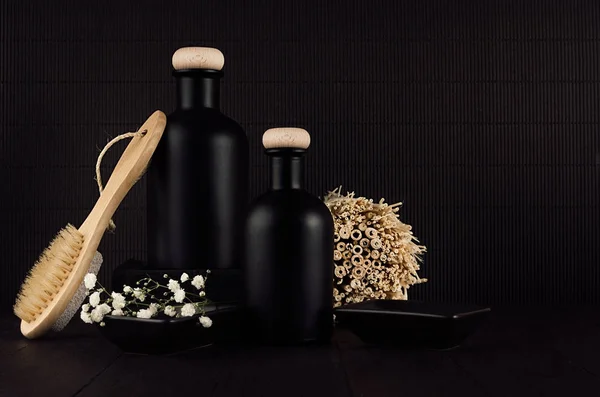 Cosmetics mock up -  blank black bottles, bath accessories, white flowers on dark wood board, copy space. Template for advertising, designers, branding identity, cover.