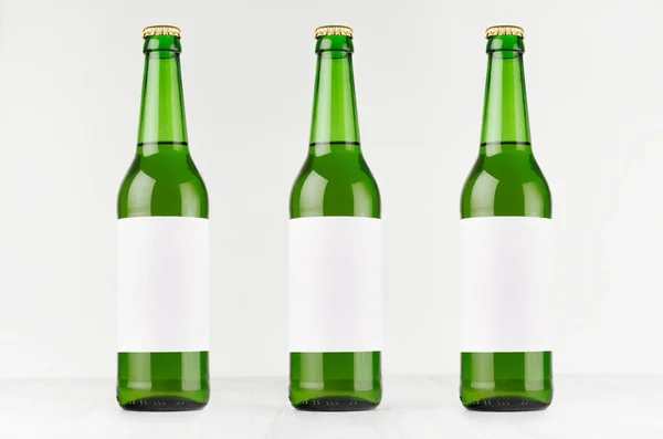 Зеленые длинноволосые пивные бутылки по 500 мл с белоснежной этикеткой на белой деревянной доске, . — стоковое фото