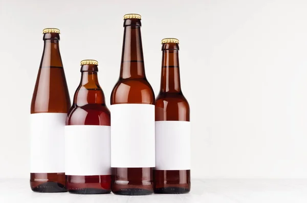 Coleção de garrafas de cerveja marrom tipo diferente com etiqueta branca em branco na placa de madeira branca, simular . — Fotografia de Stock