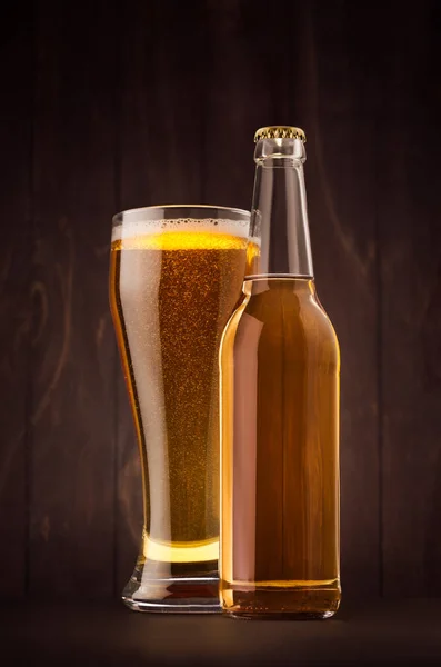 Прозора пляшка пива і склянка з золотим лайном на темно-коричневій дерев'яній дошці, вертикально, сміється . — стокове фото