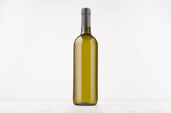 Зеленая бутылка вина с белым вином на белой деревянной доске, макет . — стоковое фото