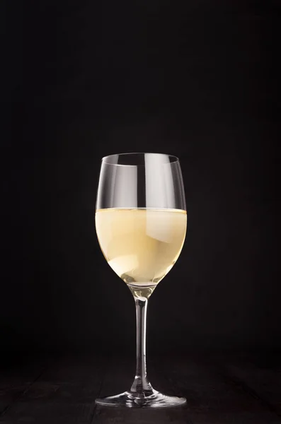 Copa de vino con vino blanco sobre fondo de madera negro oscuro elegante, espacio de copia, vertical . — Foto de Stock