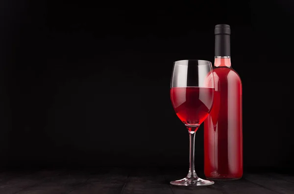 Botella de vino rosa y copa de vino se burlan de fondo de madera negro oscuro elegante, espacio de copia . — Foto de Stock