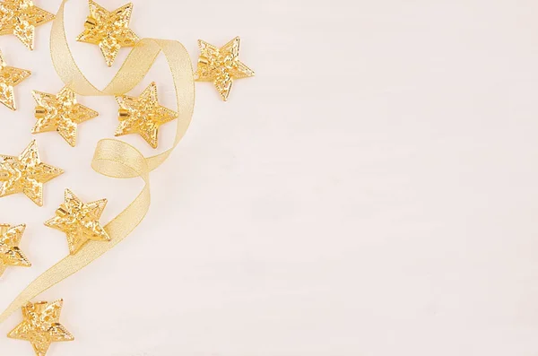 Christmas decorations, gold stars curl ribbon on soft white wooden background, copy space. — Stock Photo, Image