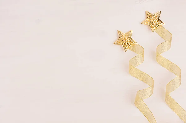 Christmas decorations, firework of gold stars and curl ribbon on soft white wooden background. — Stock Photo, Image