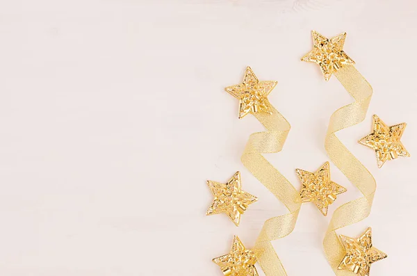 Kerstversiering, gouden sterren en krul lint op zachte witte houten achtergrond. Bovenaanzicht, kopie ruimte. — Stockfoto