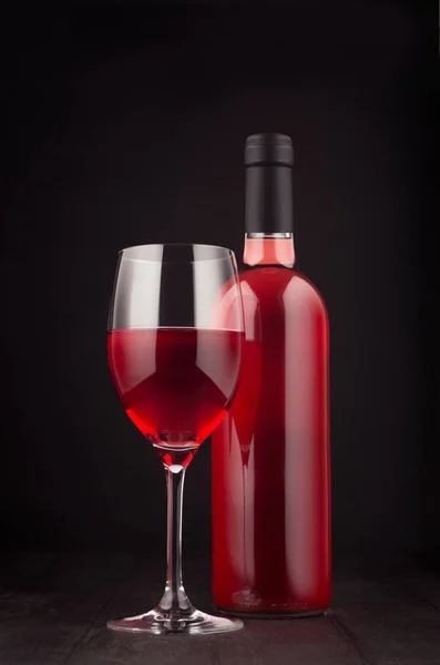 Botella de vino rosa y copa de vino se burlan de fondo de madera negro oscuro elegante, vertical . — Foto de Stock