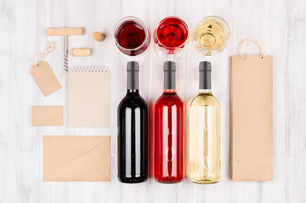 Maqueta de identidad corporativa para la industria vitivinícola: embalaje en blanco, papelería con botellas de vino tinto, blanco rosado y copas sobre fondo de madera blanca suave . — Foto de Stock