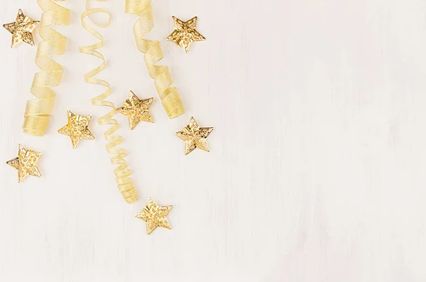 Christmas decorations, curl ribbon and gold stars falling on soft white wooden background. — Stock Photo, Image