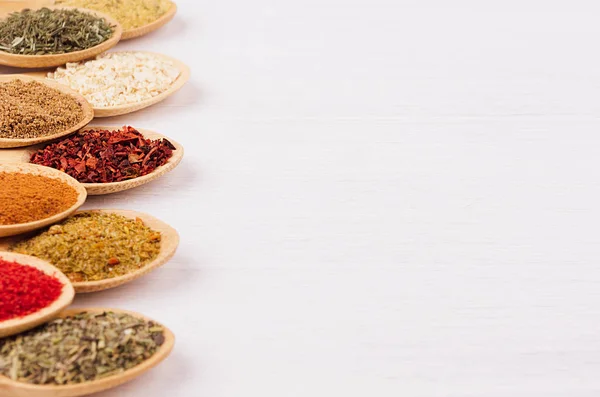 Colorful powder spices on white wooden board with copy space, closeup, texture.