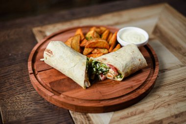 Tahta tavukla, sebzeyle ve kızarmış patatesle doldurulmuş tortilla servis ediliyor.