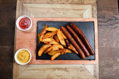 Sosis ve patatesle servis edilen restoran tabağı.