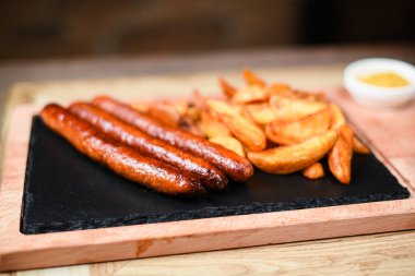 Sosis ve patatesle servis edilen restoran tabağı.