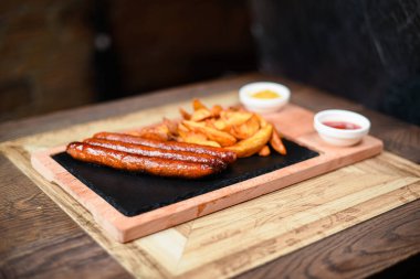 Sosis ve patatesle servis edilen restoran tabağı.