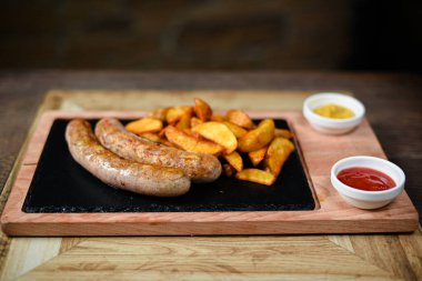 Sosis ve patatesle servis edilen restoran tabağı.