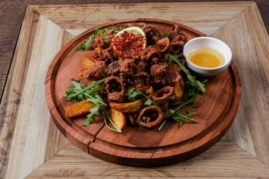 Kalamar halkaları ve patateslerle servis edilen restoran tabağı.