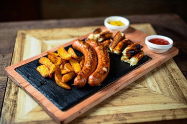 Sosis ve patatesle servis edilen restoran tabağı.