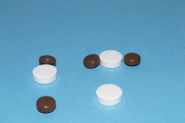 Vista lateral de comprimidos dispersos sobre fundo azul — Fotografia de Stock
