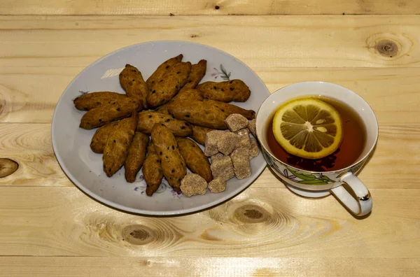 Vue du dessus de tasse de thé noir au citron et une assiette de biscuits — Photo