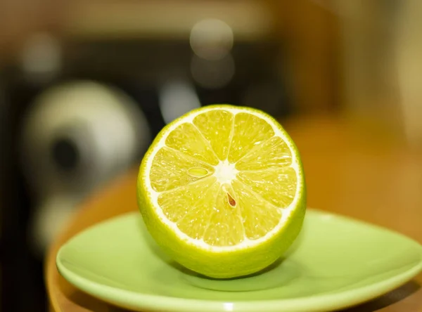 Green Lemon Fresh on plate in office. Behine lemon is cooffee ma — Stock Photo, Image