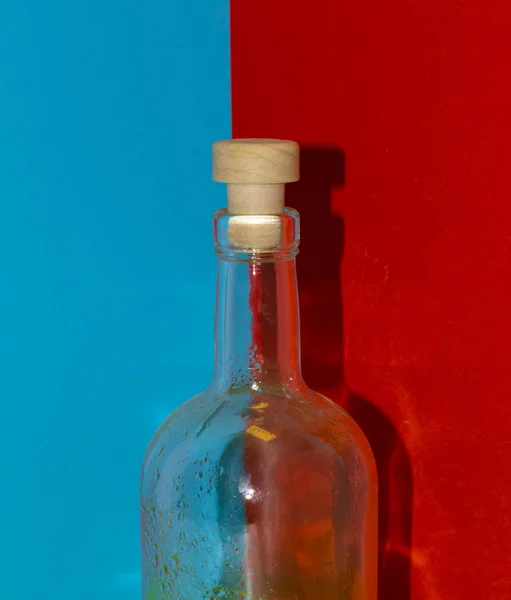 Lege fles op een blauwe en rode achtergrond — Stockfoto