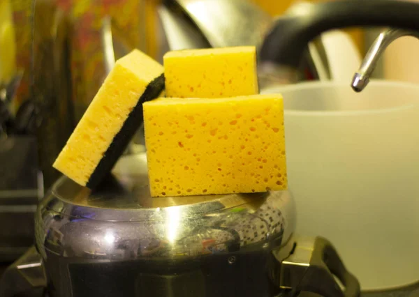 Tre gula svampar på kök över pan nära diskbänk — Stockfoto