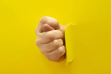 Kağıt duvardaki bir delikten gelen el başparmağı gösteriyor.