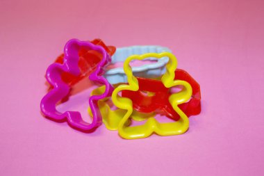 Pembe arka planda çok renkli plastik kurabiye kesiciler.