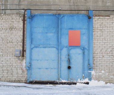 winter view of warehose with blue gate and gray bricks