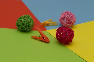 Renkli kağıt üzerinde renkli ataçlı renkli rattan topları. Yeşil top pembe ve kırmızı.