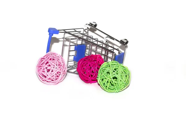 a shopping cart tipped over on its side with colorful rattan balls. objects on a white background