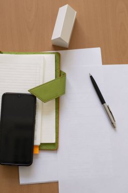 Masadaki iş hayatı konsepti akıllı telefon defteri kağıdından beyaz model ev. Üst Manzara. tahta arkaplan