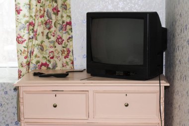 Interior of the 20th century of an old country house. TV with a kinescope on an old chest of drawers TV with a kinescope on an pink old chest of drawers clipart