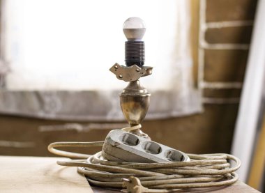 table lamp with LED lamp and a white electric extension cord blurred in construction dirt. construction site. repair in a wooden house clipart