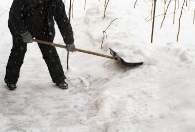 Adam evinin yakınında kar temizliyor. Verandaya giden yolu temizler. Rusya Arkhangelsk Bölgesi Kış