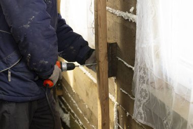 İşçi ahşap korkuluğu elektrikli tornavidayla duvara bağlar. Ahşap bir evde onarım