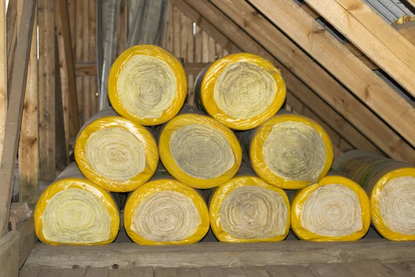 insulation rolls in yellow packaging in the attic of a wooden house. ready to use, side view.