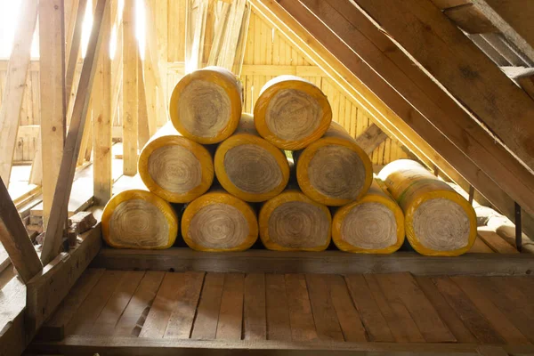 insulation rolls in yellow packaging in the attic of a wooden house. ready to use, side view.