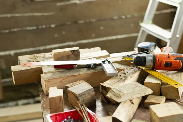 construction in a wooden house. electric screwdriver, measuring ruler, screws, boards. staircase and timber wall background