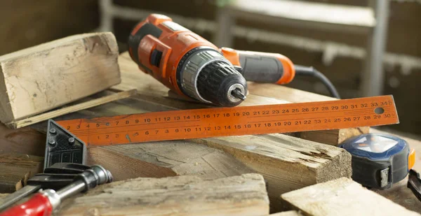 construction in a wooden house. electric screwdriver, measuring ruler, screws, boards. staircase and timber wall background