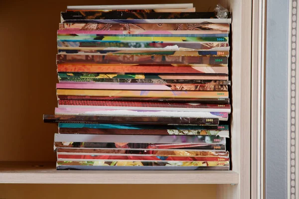 old magazines stacked on a shelf in the closet. multicolored magazines as background. close up